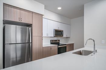 A modern kitchen with a stainless steel refrigerator and a white countertop.